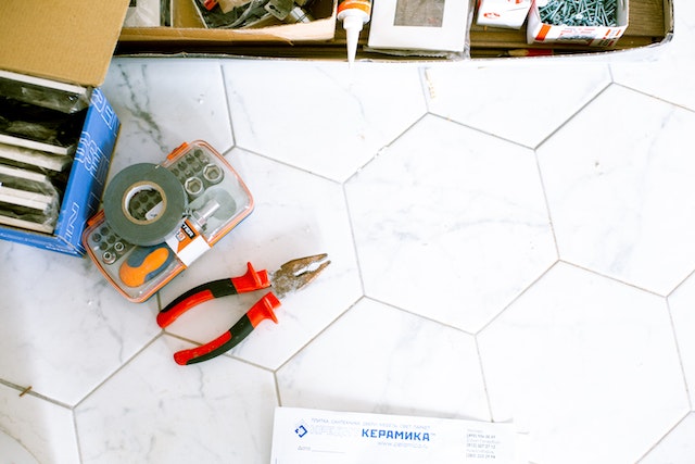 A box of tools and a pair of pliers on a marble floor.jpg